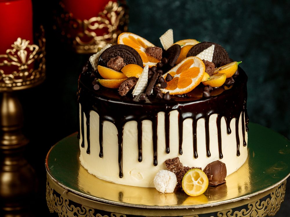 chocolate drip cake garnished with orange chocolate cookies and waffles